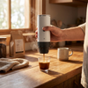Hand houdt de witte Brewza vast tijdens het zetten van koffie op een keukenblad