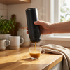 Hand houdt de mat zwarte Brewza vast met een net gezette espresso